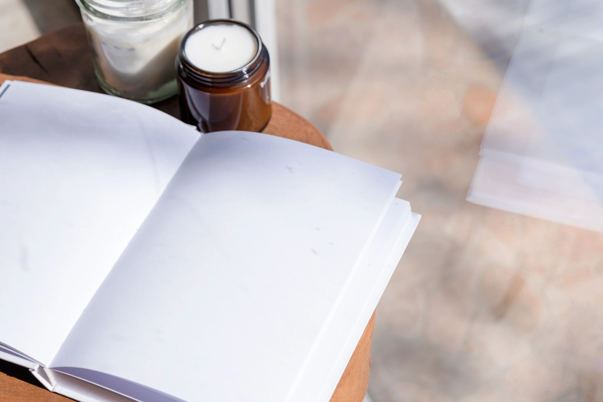 Notebook, book, and candle on a cozy wooden writing desk
